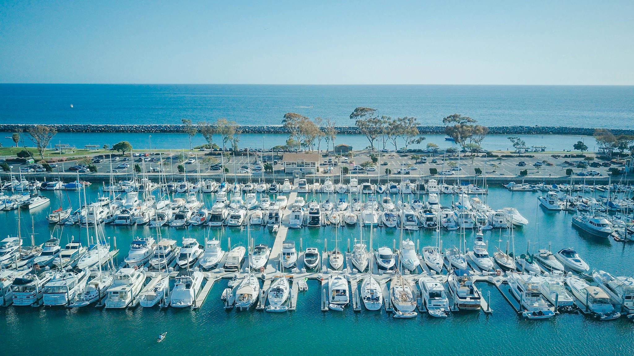 Stunning aerial view of a marina filled with yachts under a clear blue sky, perfect for summer exploration.